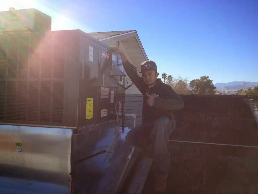 HVAC technician performing Air Duct Repair on a rooftop unit in La Grange